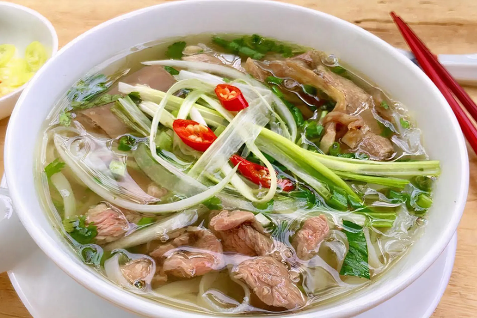 /SEO-images/2025 SEO/Traffic TA/MN/vietnamese-breakfast/vietnamese-breakfast/steaming-bowl-of-pho-bo-with-fresh-herbs-and-lime-wedges-on-the-side