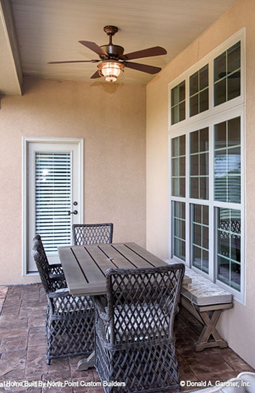 The back porch offers an outdoor dining set comprised of a wooden dining table, wicker chairs, and a cushioned bench.