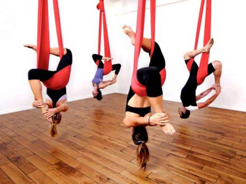 group of persons doing aerial yoga