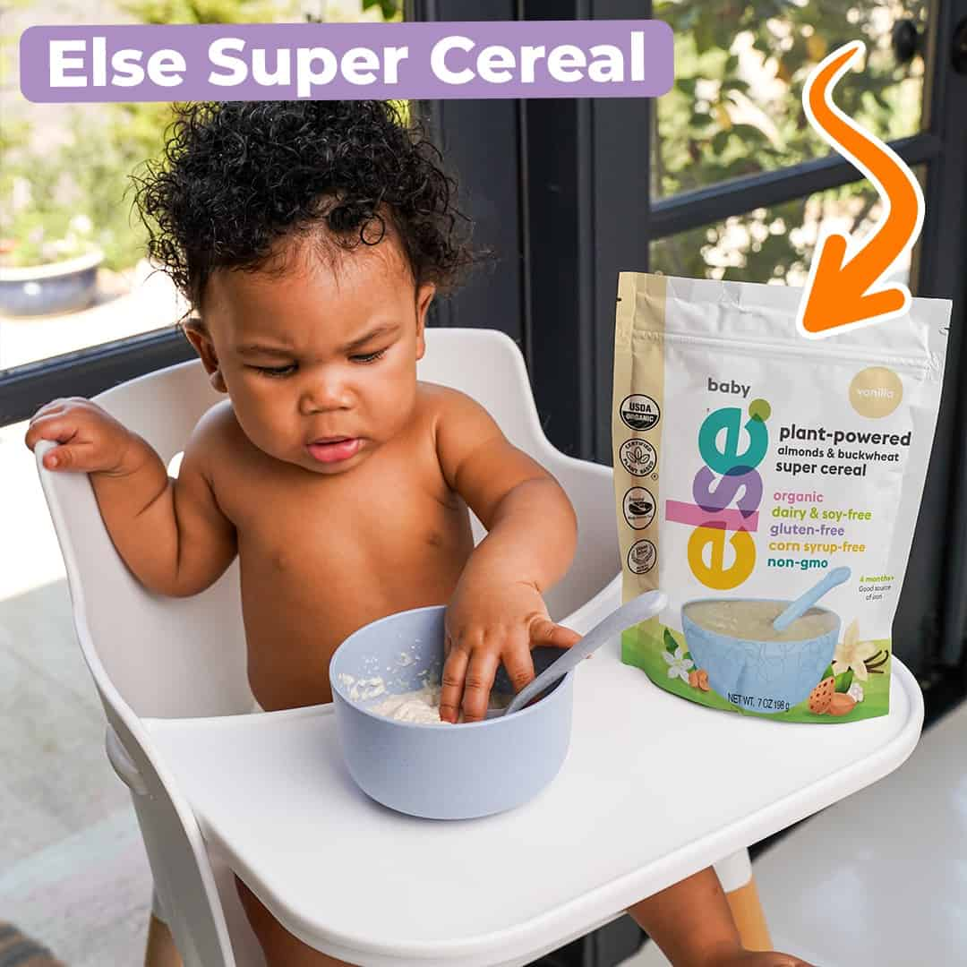 A baby sitting in a high chair, happily eating cereal from a bowl placed in front of them.