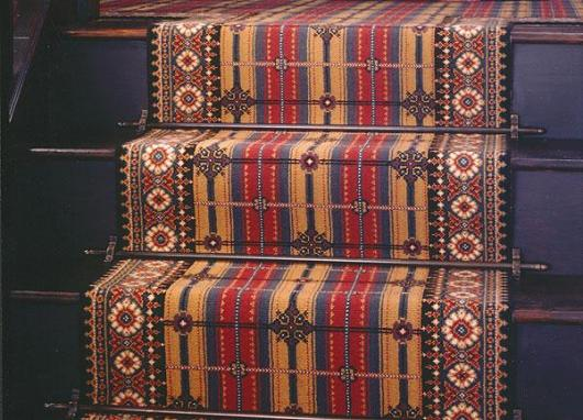 Stairs with patterned carpet and stair rods. 