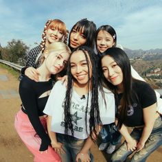 This may contain: a group of young women standing next to each other on top of a dirt road