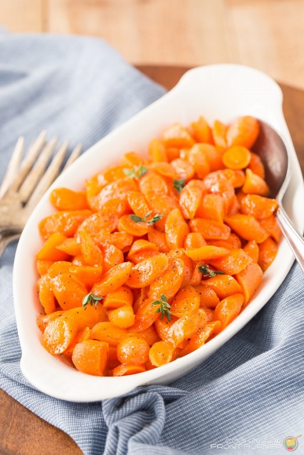 Easy bourbon honey glazed carrots in a white serving dish with a spoon