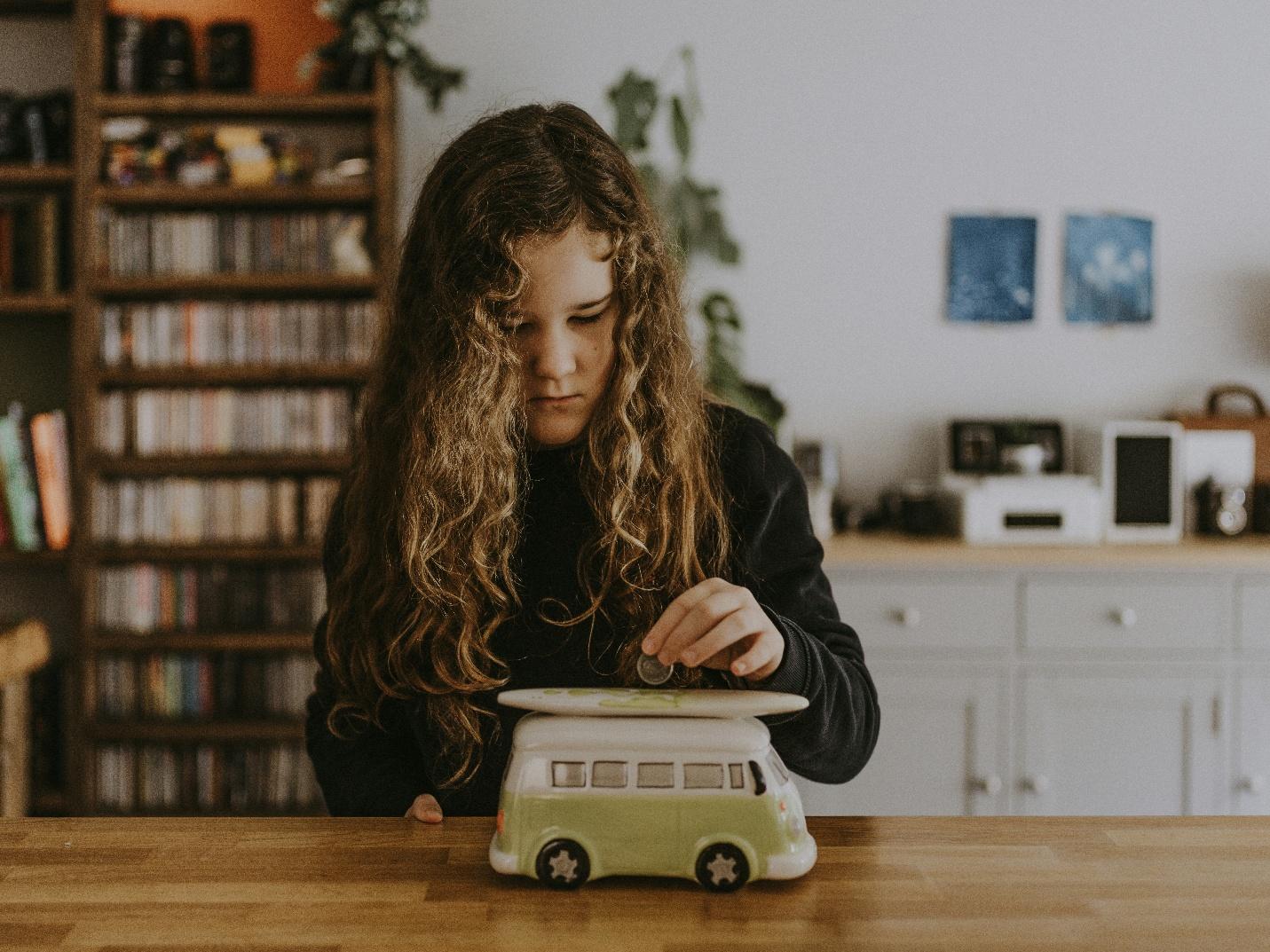 A child putting a coin into a toy car

AI-generated content may be incorrect.