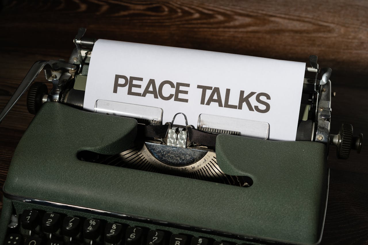 A vintage green typewriter with a paper sheet titled 'PEACE TALKS' inserted, symbolizing the creation of thoughtful content, similar to structuring online courses on topics like conflict resolution.