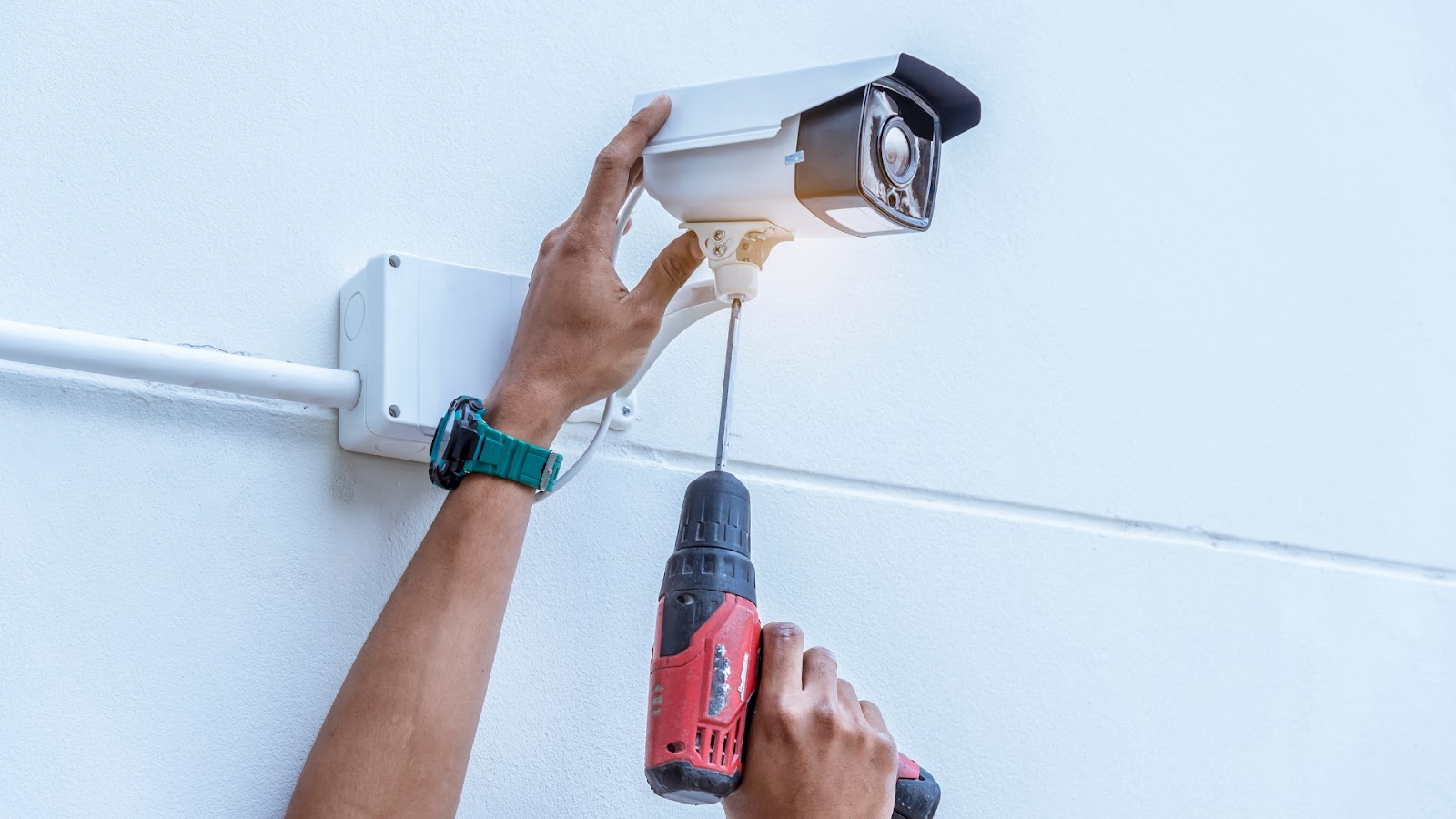 A technician installing a security camera around the garage door