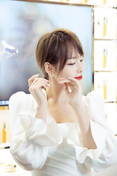 This contain Zhang Jiani in a white dress holding her hand up to her face and looking at the mirror