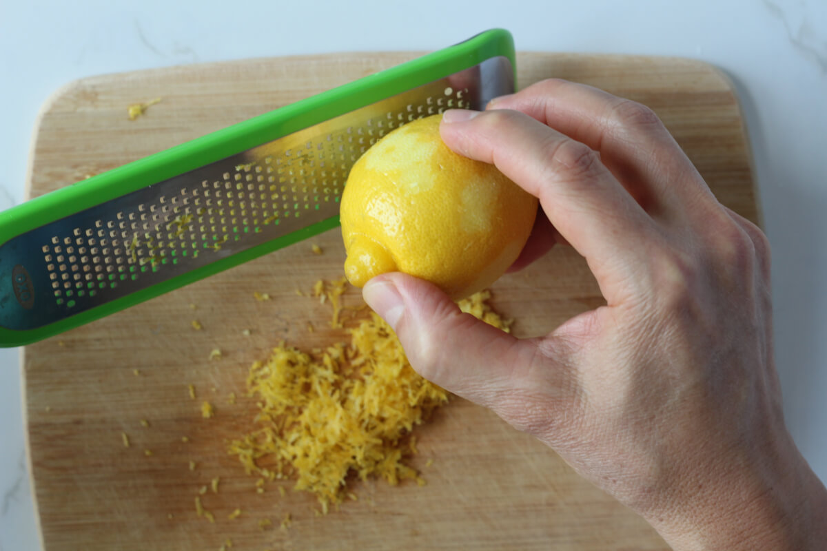 Zesting lemon with microplane over cutting board