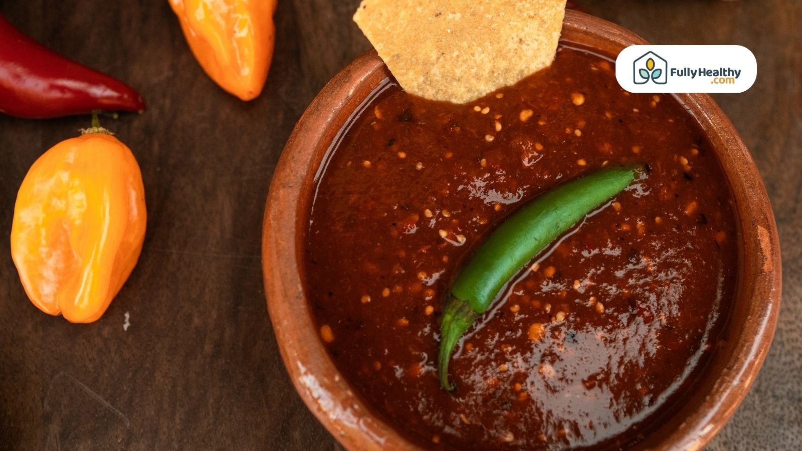 Dark red salsa with green chili and tortilla chip on top