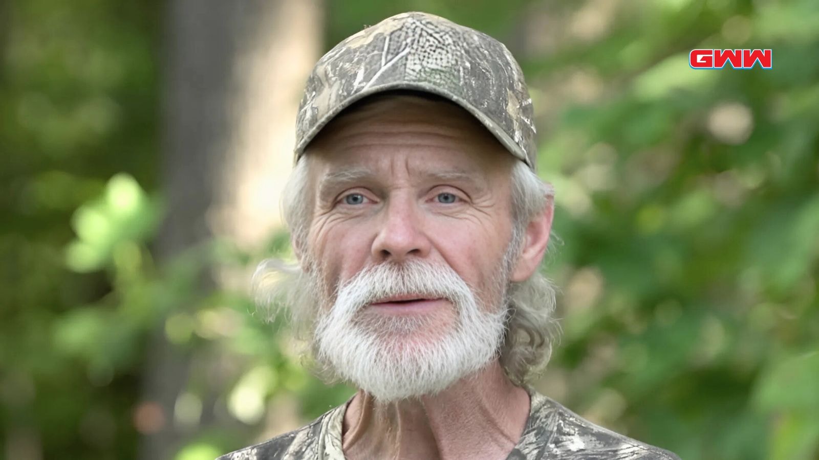 Kenny with white beard wearing camouflage cap in nature.