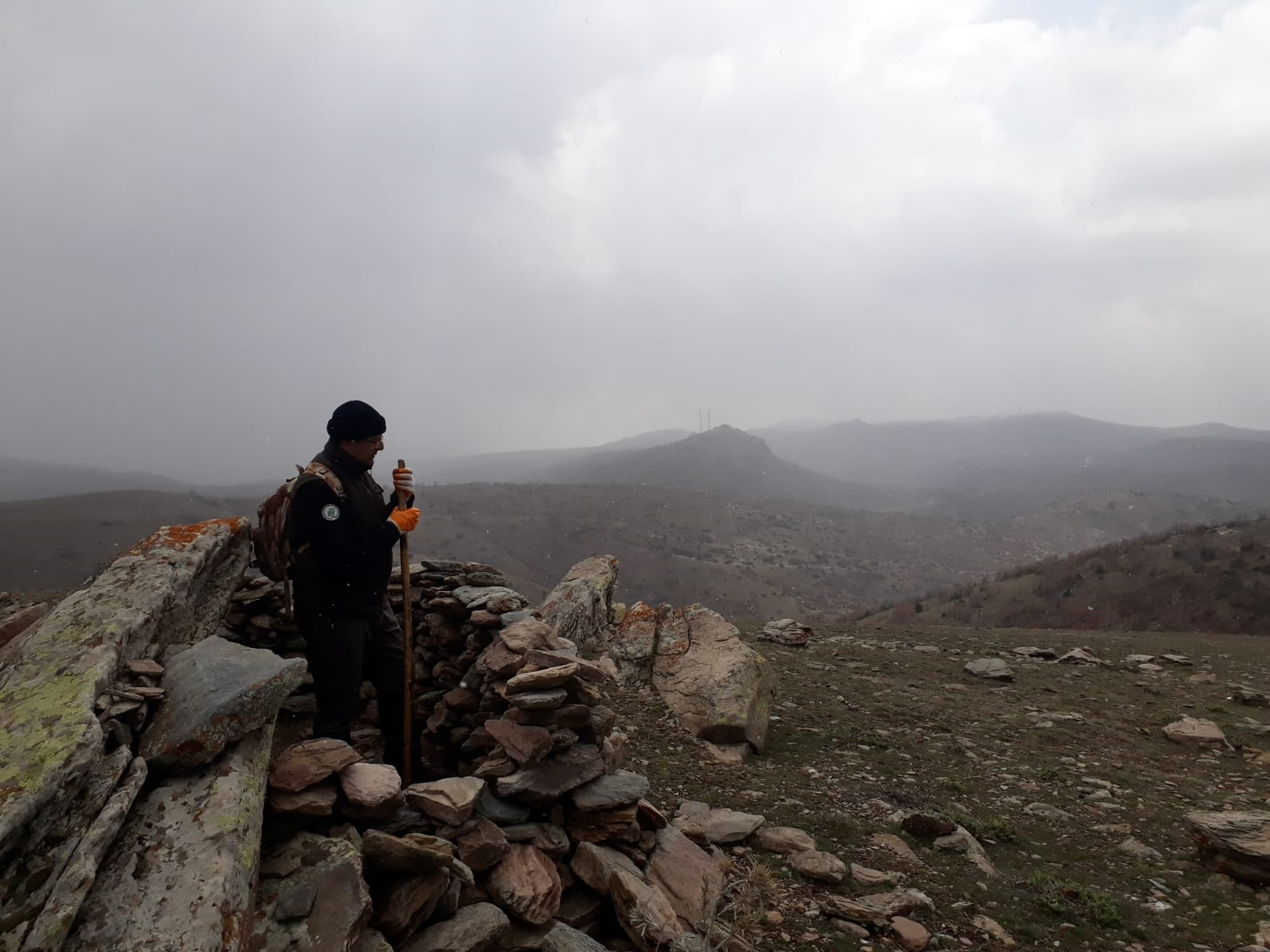 A person standing on a rocky hill

Description automatically generated