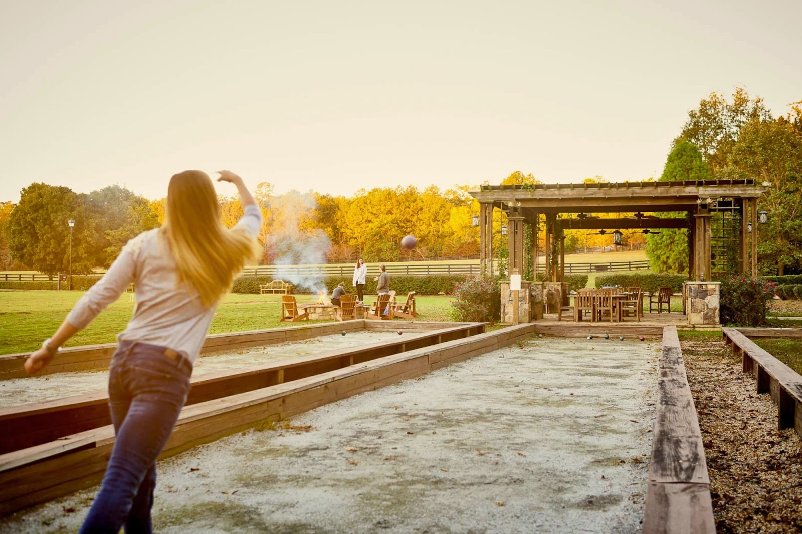 A woman playing bocce ball outside.