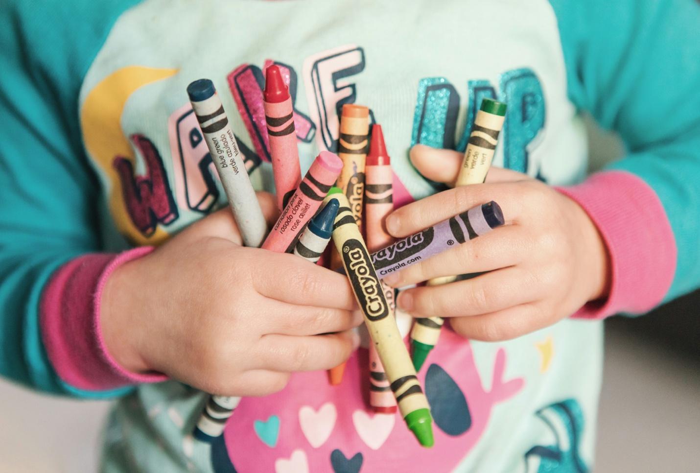 A child holding crayons in their hands

Description automatically generated