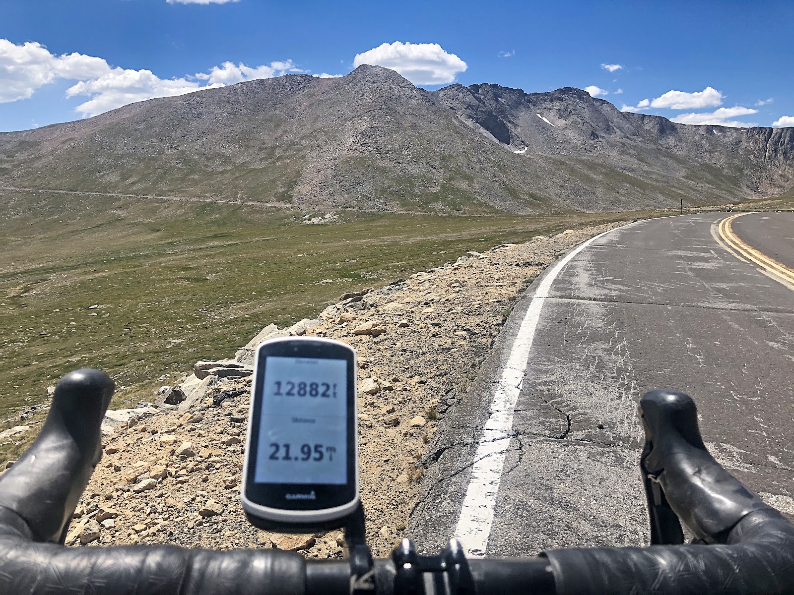 Cycling Mt. Evans, Colorado - view of bike handlebars and Garmin on roadside overlooking mountain ranges, Garmin reads 12,882 feet