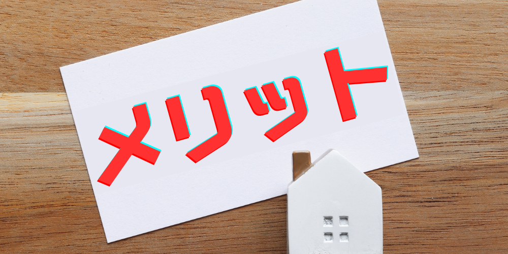 木目の上に白色の家のミニチュアと赤字で「メリット」と書かれたカード
