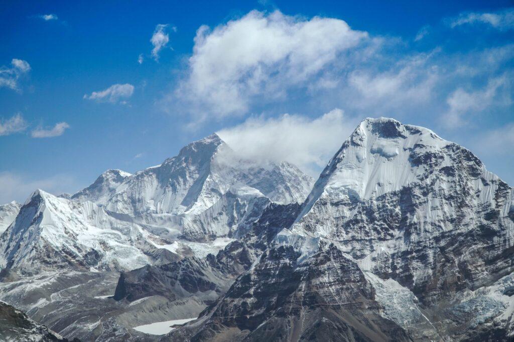 A snowy mountain tops with clouds in the sky

Description automatically generated