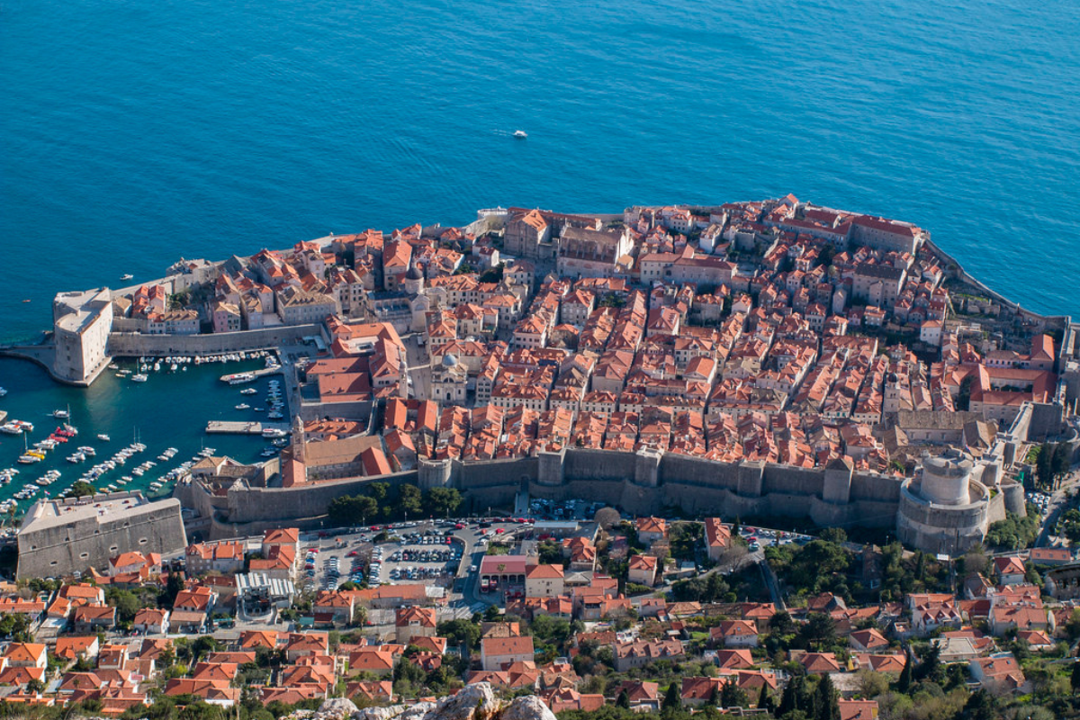 Blue clean and clear water in the sea and group of houses are there and cruises are parked in water
