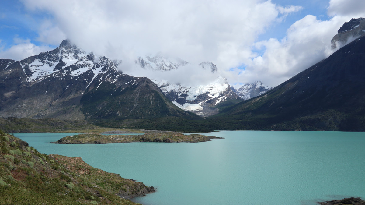 Still lake with snow-covered mountains in the background.