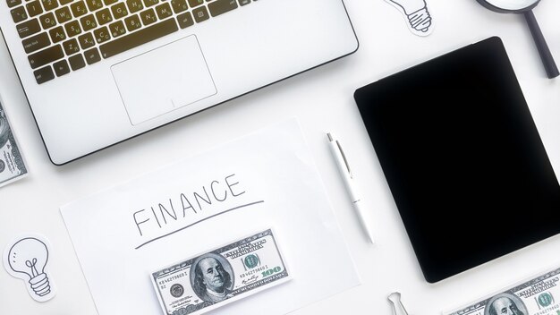 Table with finance work stuff. Laptop, money, tablet, pen, papers