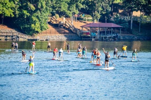 A group of people on paddle boards in a lake Description automatically generated