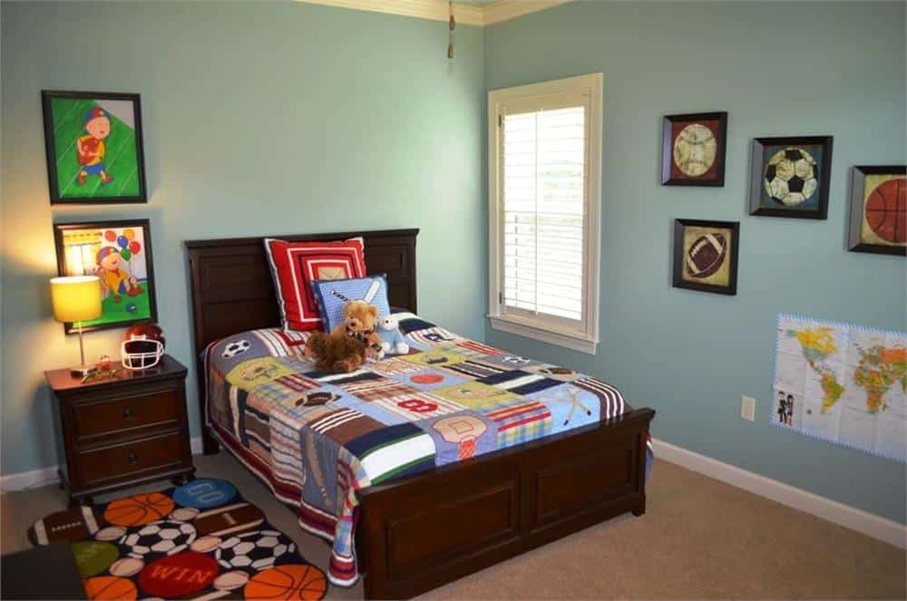 Kid's bedroom with wooden furnishings, carpet flooring, and blue walls graced with framed artworks.