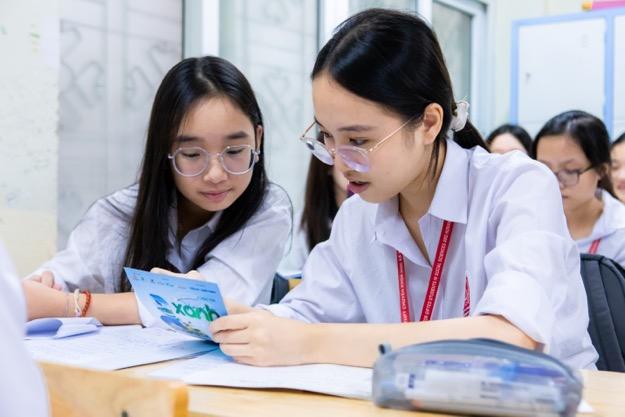 A group of girls looking at a piece of paper Description automatically generated