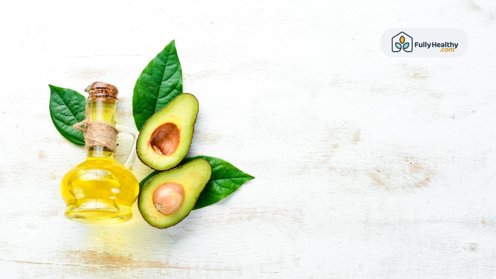 Rustic bottle of avocado oil with avocado halves and green leaves