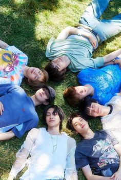 This contain an image of RIIZE Group members  laying on the grass in a circle looking up at something with their eyes closed