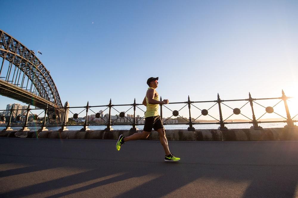 man in yellow tank top running near shore