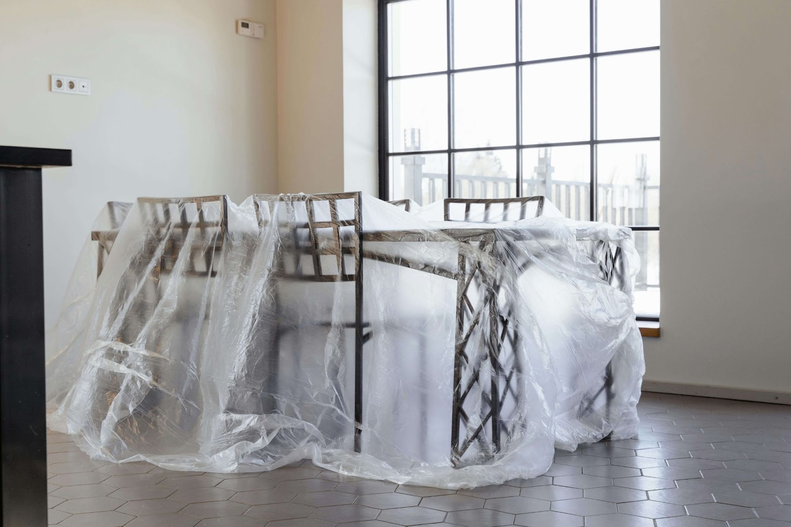 A dining set covered in a large and clear plastic tarp.