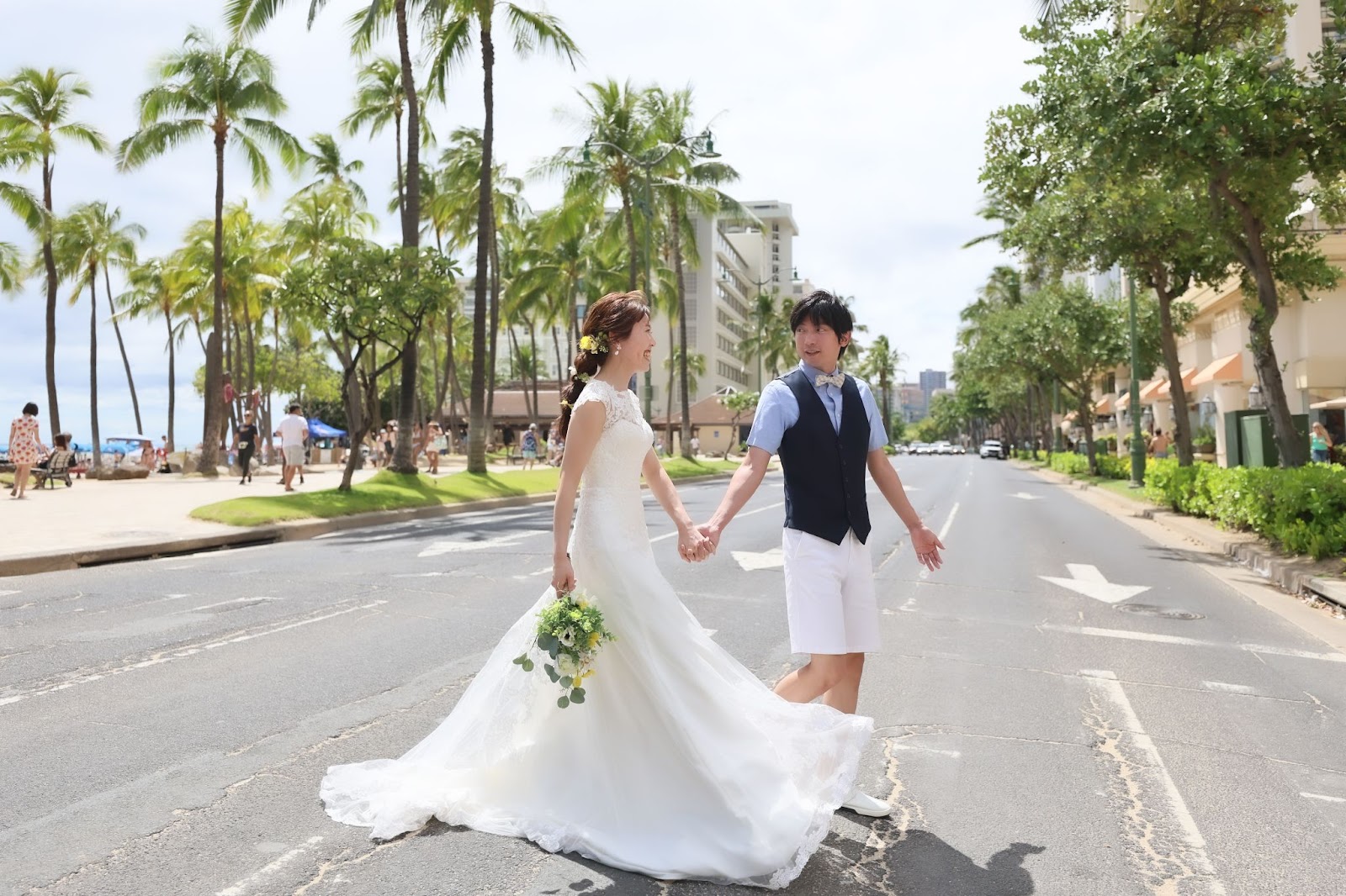 ハワイのワイキキタウンの道路を歩いているウェディングドレス姿のカップル