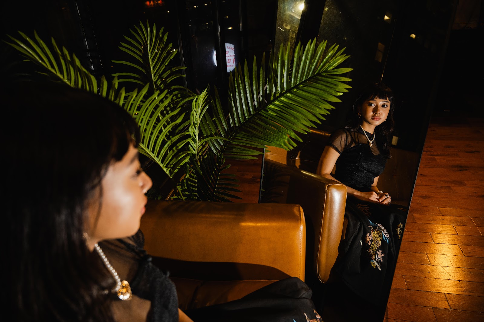 Aww Myat May stares into the mirror in a dim backdrop with warm light. 