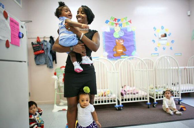 Black woman carrying baby at a day care center