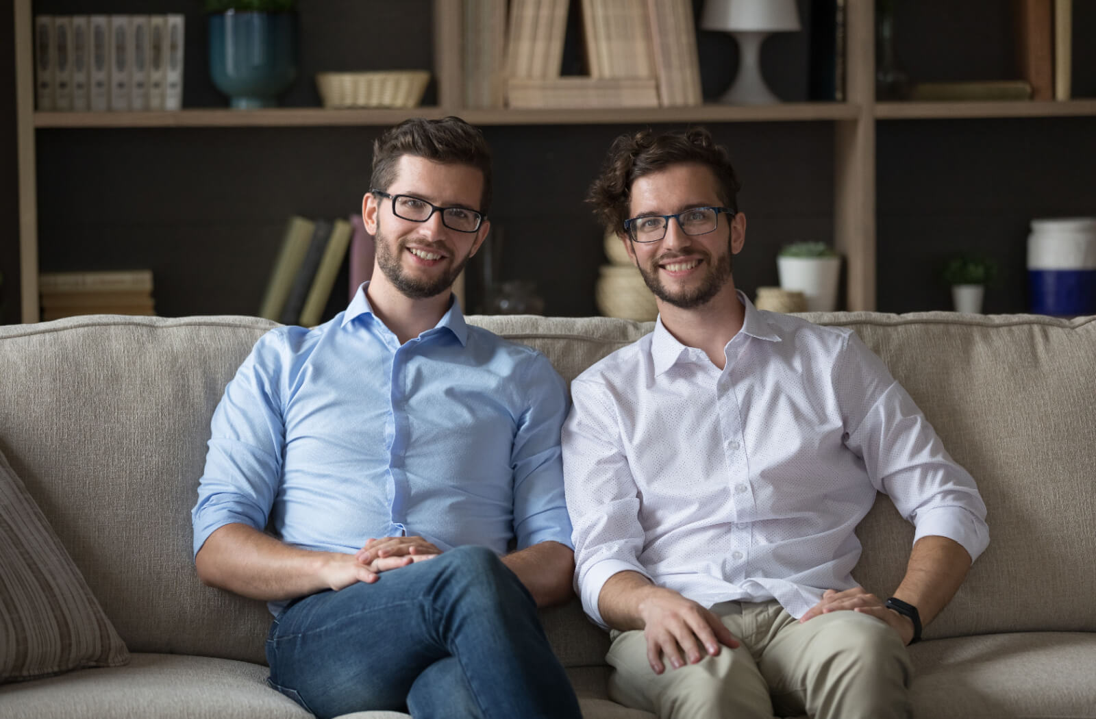 Two adult siblings sitting on the couch together and smiling after a discussion about their aging parents.
