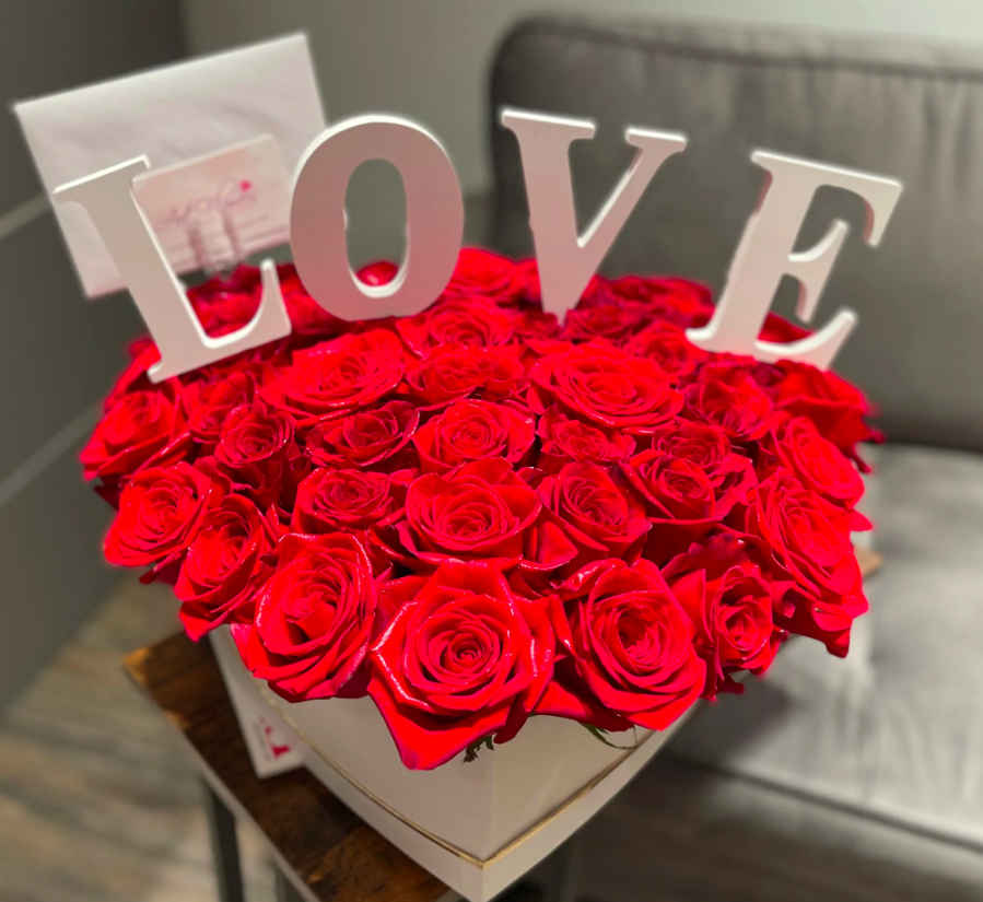 A romantic display of vibrant red roses arranged elegantly around a decorative LOVE monogram, symbolizing affection and passion.