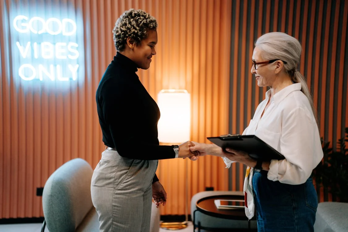 Welcoming new employee handshake illustrating benefits of onboarding in a modern office