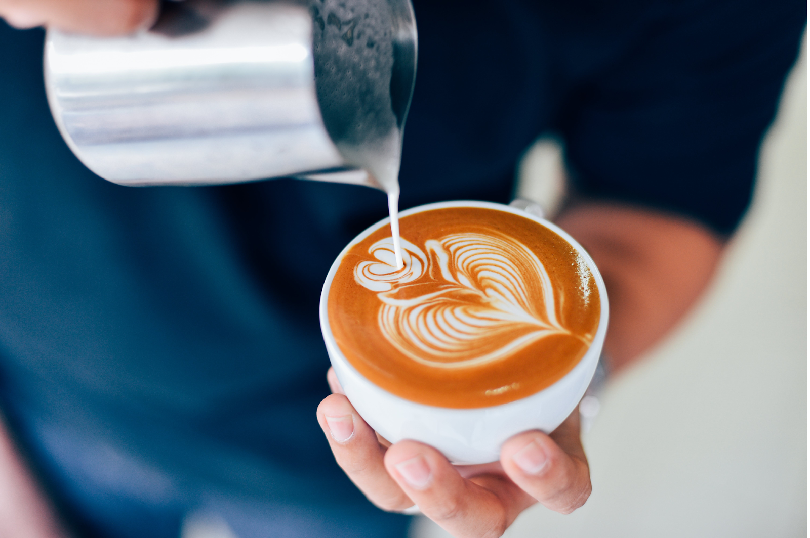 A barista creating latte art using milk substitutes.