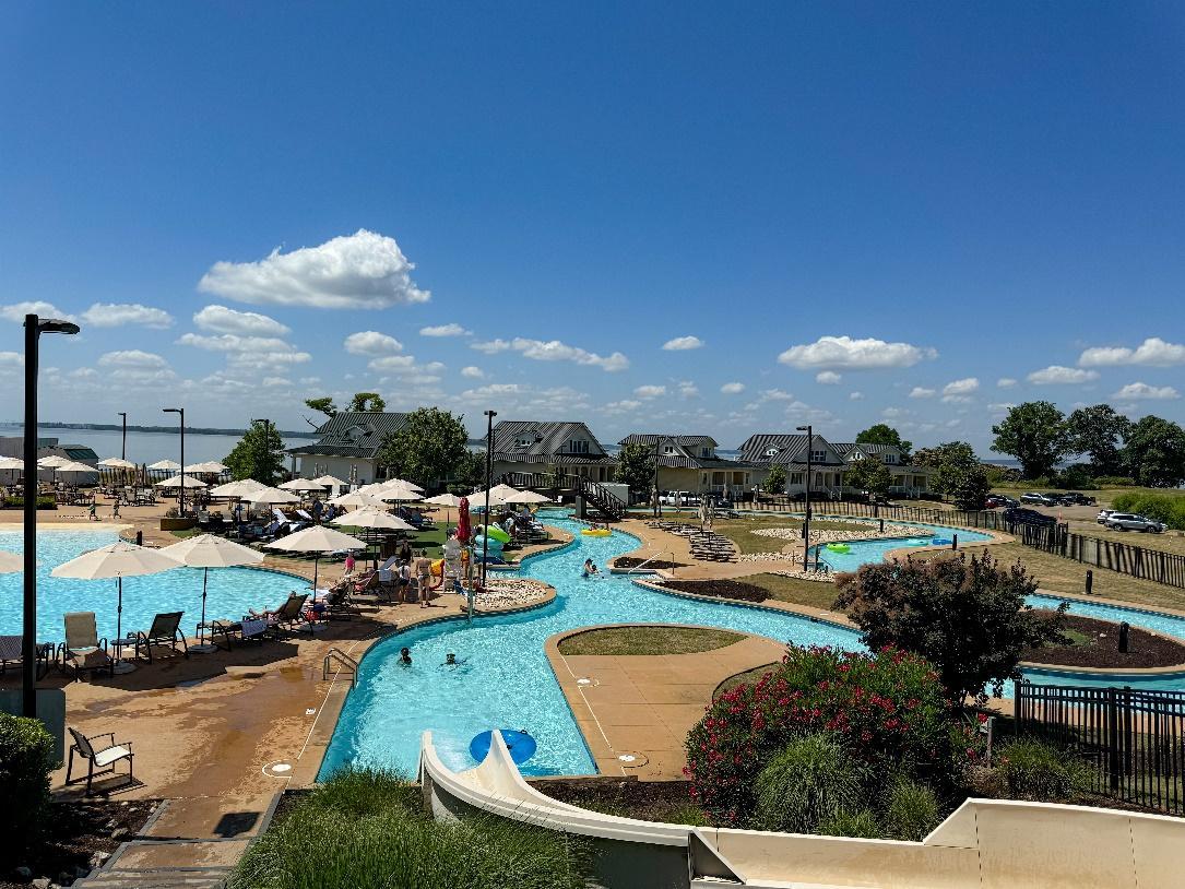 A pool with umbrellas and people in it

Description automatically generated