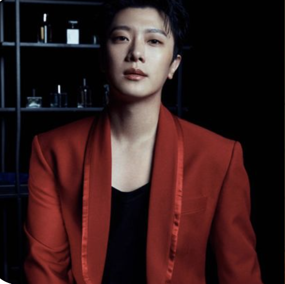 A picture of Minhwan on a red suit and a black vest 