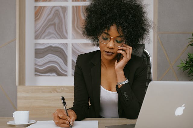 A person on a phone call taking notes.