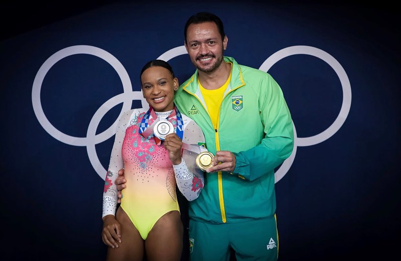 Rebeca Andrade e seu treinador com suas medalhas de ouro e prata das Olimpíadas de 2020, em Tóquio