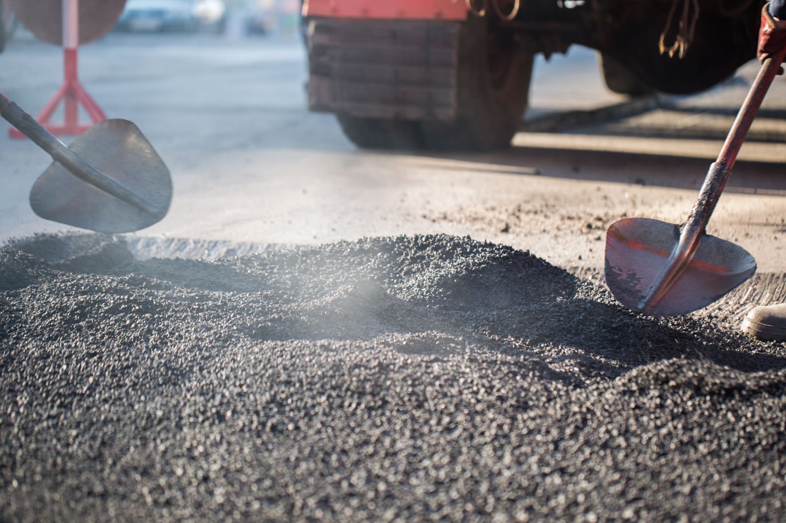 Workers with shovels working with asphalt. 