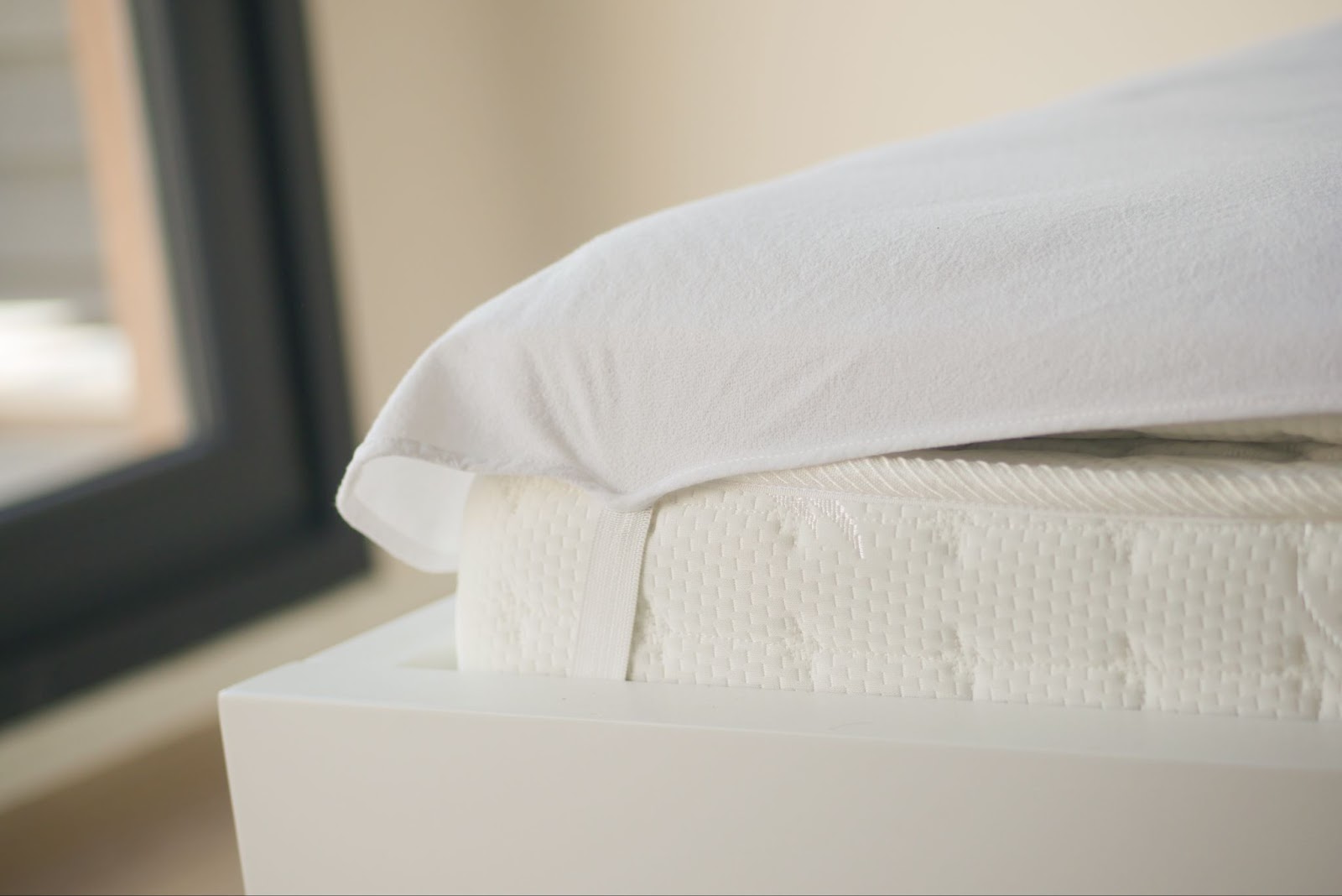 Close-up of a mattress with a fitted white cover and mattress topper illustrating what is a mattress topper and its benefits.