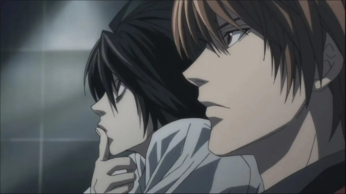 L y Light Yagami de Death Note sentados juntos, cada uno con una expresión seria mientras planean su próximo movimiento, escena icónica de la serie de anime.