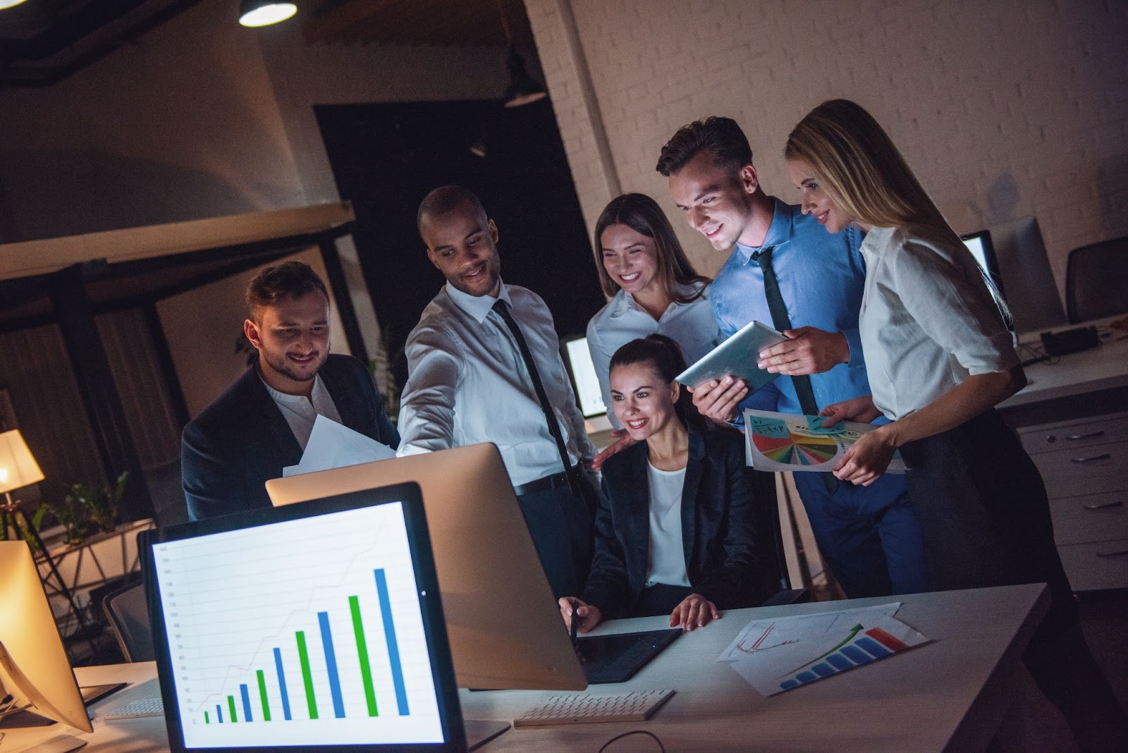 Group of business people sitting around a computer and using tablets. 