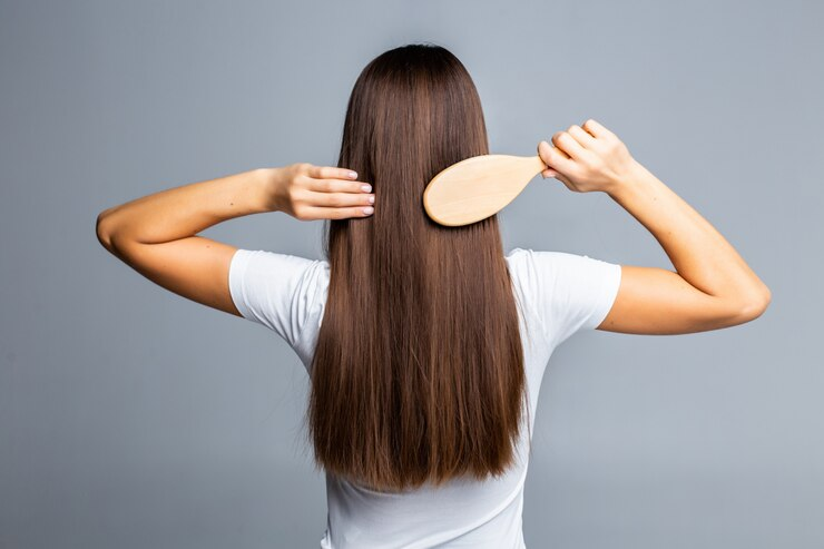 Back view of a woman combing her straight hair