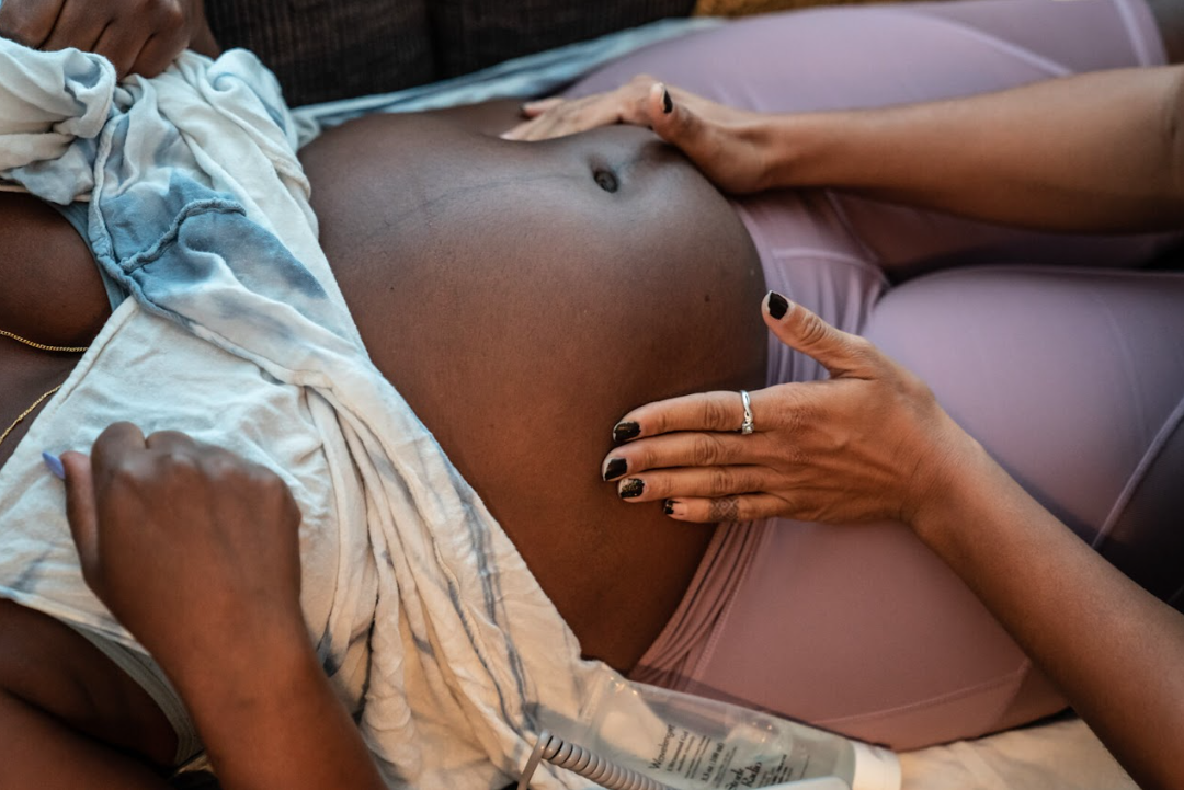 Photo of a pregnant belly being held by someone's hands.