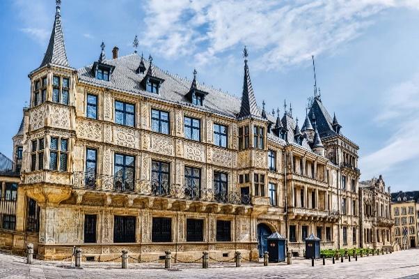 A large building with many windows with Grand Ducal Palace, Luxembourg in the backgroundDescription automatically generated