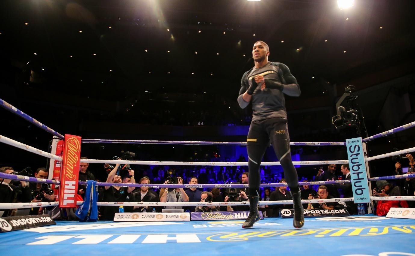 A person standing in a boxing ring with a crowd watching  Description automatically generated