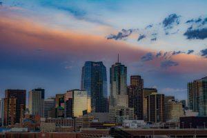 Denver city skyline at sunset with buildings reflecting the colorful sky.